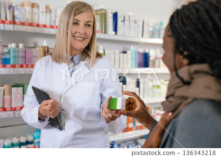 Mature pharmacist advising young sick african american on medicines to use Mature pharmacist advising young sick african american on medicines to use 136343218