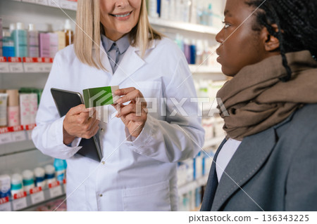 Sick african american girl talking to a pharmacist in a drug store Sick african american girl talking to a pharmacist in a drug store 136343225