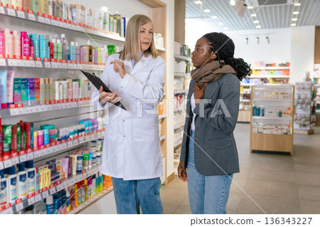 Sick african american girl talking to a pharmacist in a drug store Sick african american girl talking to a pharmacist in a drug store 136343227
