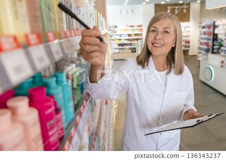 Blonde caucasian pharmacist doing inventarization in a drug store Blonde caucasian pharmacist doing inventarization in a drug store 136343237