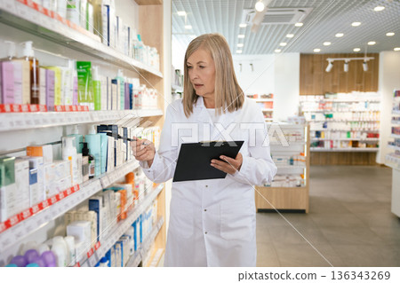 Mature blonde pharmacist in a lab coat in a drug store 136343269