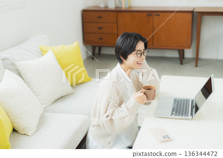 A woman watching a computer at home 136344472
