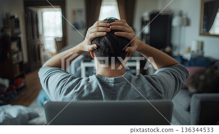 A tired man sits at a laptop, clutching his head. Concepts of overwork, work-life balance, mental fatigue, and reassessing the value of employment. A tired man sits at a laptop, clutching his head. Concepts of overwork, work-life balance, mental fatigue, and reassessing the value of employment. 136344533