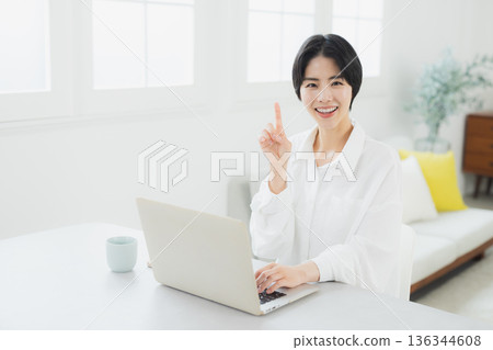 A woman watching a computer at home A woman watching a computer at home 136344608
