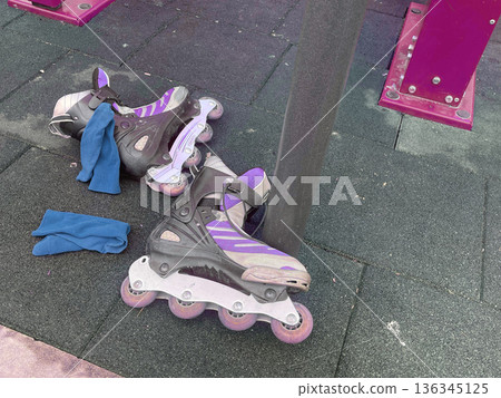 Roller skates and blue cloth placed near a pole at a playground during the afternoon in a city park Roller skates and blue cloth placed near a pole at a playground during the afternoon in a city park 136345125