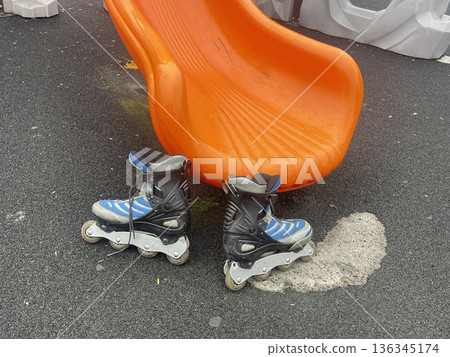 Roller skates placed near an orange slide at a playground during afternoon playtime on a sunny day Roller skates placed near an orange slide at a playground during afternoon playtime on a sunny day 136345174