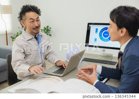 Engineers having a meeting while looking at documents at the office Engineers having a meeting while looking at documents at the office 136345344