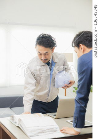 工程師們在辦公室一邊開會一邊查看文件。 136345349