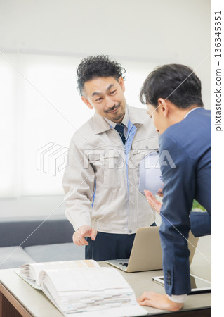 工程師們在辦公室一邊開會一邊查看文件。 工程師們在辦公室一邊開會一邊查看文件。 136345351