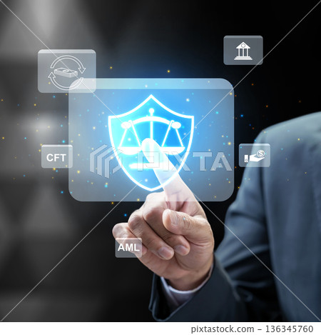Businessman interacting with a futuristic digital interface for AML and CFT compliance, featuring a legal shield and scales representing financial security and regulatory law Businessman interacting with a futuristic digital interface for AML and CFT compliance, featuring a legal shield and scales representing financial security and regulatory law 136345760