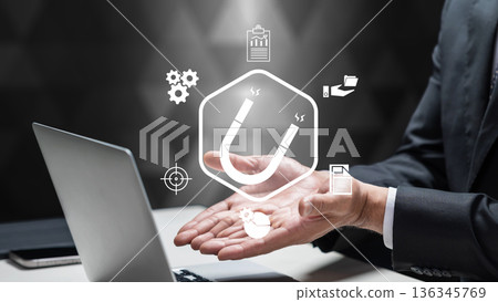 A businessman uses a laptop with a digital magnet icon, representing lead generation and customer attraction strategies to grow business and reach target audiences 136345769