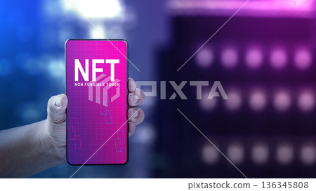 Hand holding a smartphone displaying NFT Non Fungible Token text over a neon bokeh background. Concept of digital assets, blockchain technology, and cryptocurrency investment Hand holding a smartphone displaying NFT Non Fungible Token text over a neon bokeh background. Concept of digital assets, blockchain technology, and cryptocurrency investment 136345808