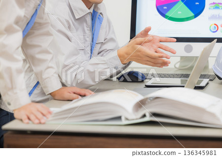 工程師們在辦公室一邊開會一邊查看文件。 工程師們在辦公室一邊開會一邊查看文件。 136345981
