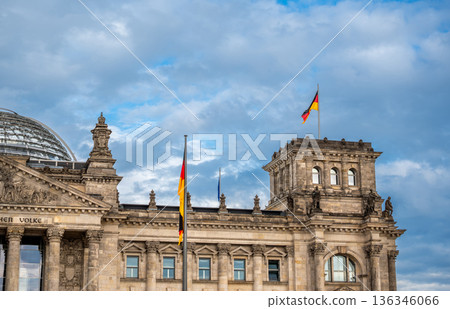 Berlin, germany, august 12, 2023. Reichstag building facade in berlin, germany. German flags waving from the historic parliament building under a blue sky with clouds 136346066