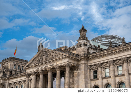Berlin, germany, august 12, 2023. Reichstag building in berlin with german flag and glass dome against blue sky, symbol of parliament, democracy and national heritage 136346075