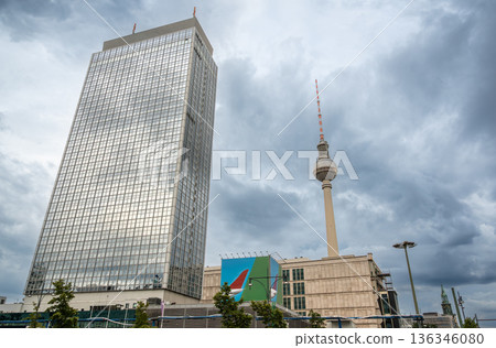 Berlin, germany, august 12, 2023. Berlin tv tower and a glass facade skyscraper dominating the city skyline under a dramatic cloudy sky near alexanderplatz Berlin, germany, august 12, 2023. Berlin tv tower and a glass facade skyscraper dominating the city skyline under a dramatic cloudy sky near alexanderplatz 136346080
