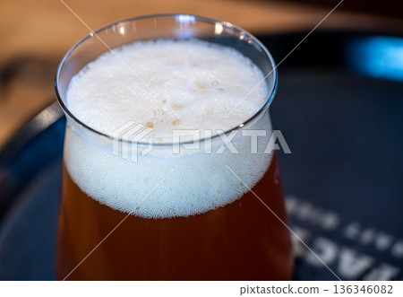 Berlin, germany, august 12, 2023. Craft beer in a glass creating a frothy white head, offering refreshment and a delicious alcoholic beverage experience Berlin, germany, august 12, 2023. Craft beer in a glass creating a frothy white head, offering refreshment and a delicious alcoholic beverage experience 136346082