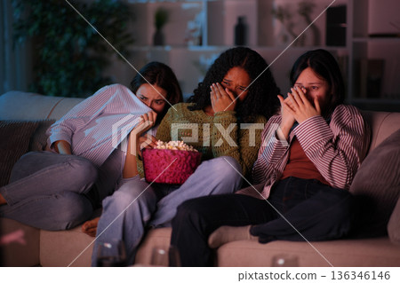 Terrified diverse friends watching horror movie on tv Terrified diverse friends watching horror movie on tv 136346146