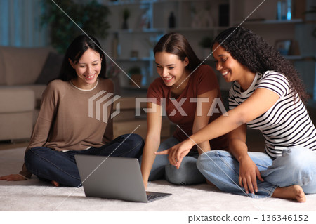 Three diverse friends checking laptop content in the night at home Three diverse friends checking laptop content in the night at home 136346152