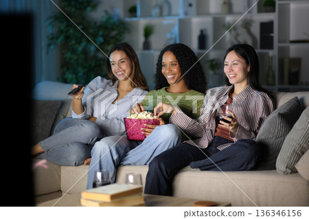 Three diverse happy friends watching tv in the night Three diverse happy friends watching tv in the night 136346156