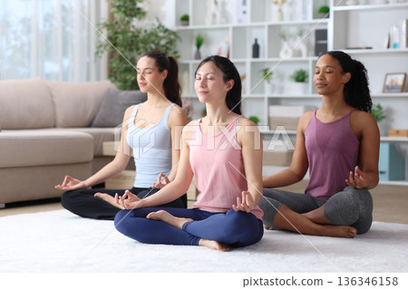 Three friends doing yoga exercises at home 136346158