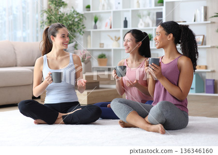 Three friends drinking and talking after yoga at home 136346160