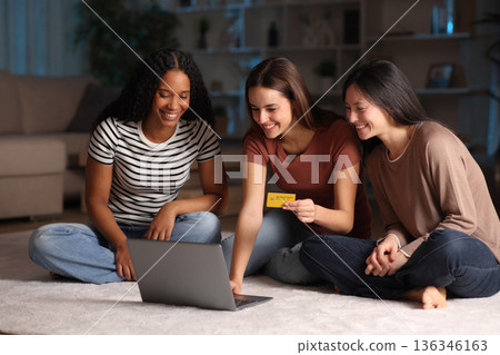 Three happy friends buying online at home in the night Three happy friends buying online at home in the night 136346163