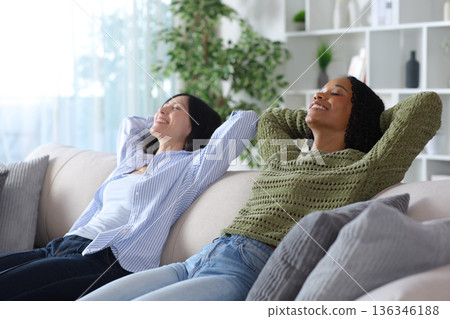 Diverse women relaxing sitting on a couch at home Diverse women relaxing sitting on a couch at home 136346188