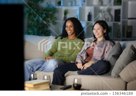 Happy diverse couple watching tv in the night at home 136346189