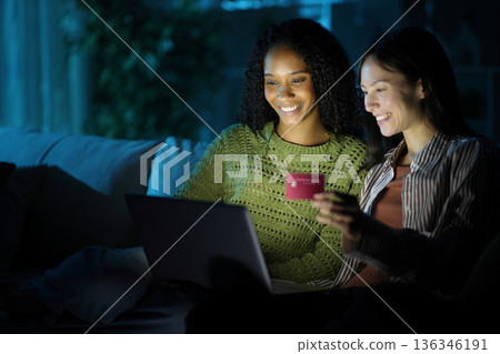 Happy diverse women buying online in the night at home Happy diverse women buying online in the night at home 136346191