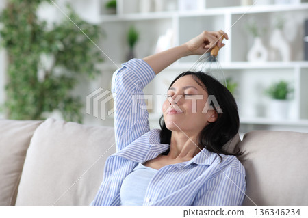 Asian woman self massaging head using scratcher Asian woman self massaging head using scratcher 136346234