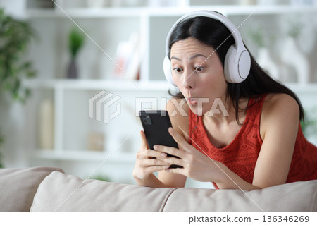 Surprised asian woman watching media on phone Surprised asian woman watching media on phone 136346269