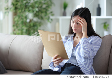 Worried asian woman checking documents at home 136346274