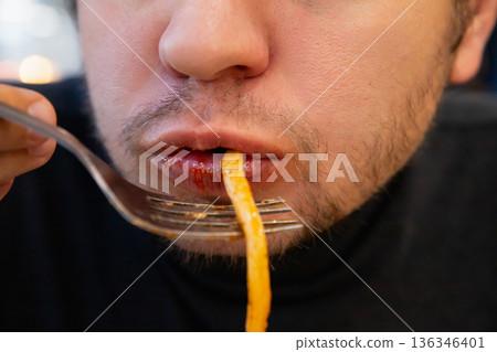 man eats fat pasta, sucks it with his mouth showcasing overeating and unhealthy eating habits. concept of obesity, diabetes, gluttony, diabetes, overeating, close-up of chewing mouth man eats fat pasta, sucks it with his mouth showcasing overeating and unhealthy eating habits. concept of obesity, diabetes, gluttony, diabetes, overeating, close-up of chewing mouth 136346401