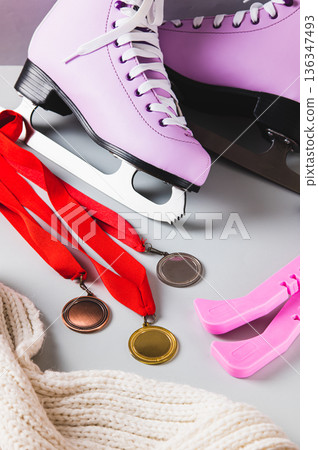 Figure skating skates, medals, covers and a scarf on a light background vertical view 136347493