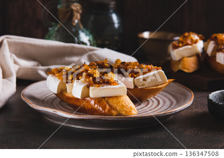 Snack sandwiches with brie cheese and caramelized onions on a plate on the table 136347508