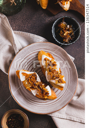 Toasts with creamy brie cheese and caramelized onions on a plate top and  vertical view 136347514