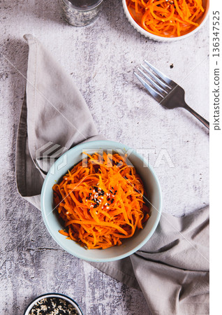 Spicy Korean carrots with sesame seeds in a bowl on the table top and vertical view 136347525