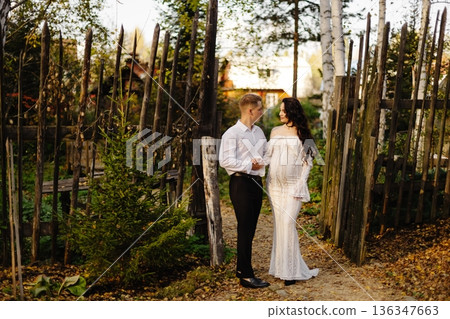 Loving expecting couple standing near rustic wooden fence Loving expecting couple standing near rustic wooden fence 136347663