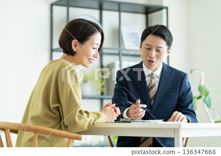 一位商人向一位中年婦女推銷商品。 136347668