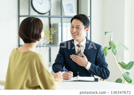 一位商人向一位中年婦女推銷商品。 一位商人向一位中年婦女推銷商品。 136347672