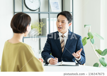 A businessman selling to a middle-aged woman 136347673