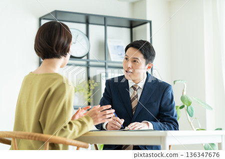 一位商人向一位中年婦女推銷商品。 一位商人向一位中年婦女推銷商品。 136347676