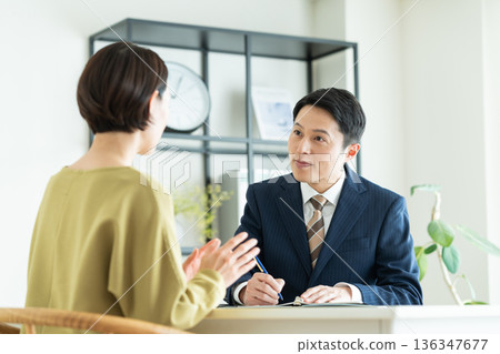 一位商人向一位中年婦女推銷商品。 136347677