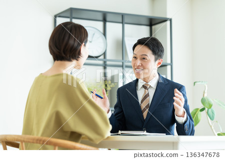 一位商人向一位中年婦女推銷商品。 136347678