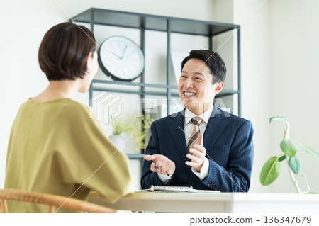 一位商人向一位中年婦女推銷商品。 一位商人向一位中年婦女推銷商品。 136347679