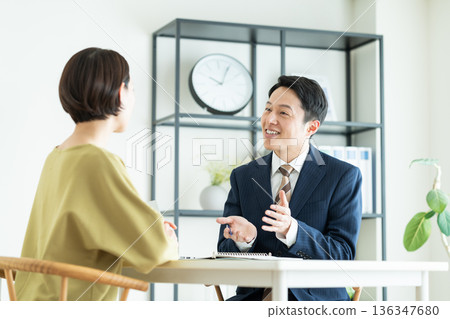 一位商人向一位中年婦女推銷商品。 一位商人向一位中年婦女推銷商品。 136347680