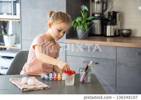 Child dipping brush into jar of paint for egg decoration. Ritualistic preparation for festive activity. Child dipping brush into jar of paint for egg decoration. Ritualistic preparation for festive activity. 136348197