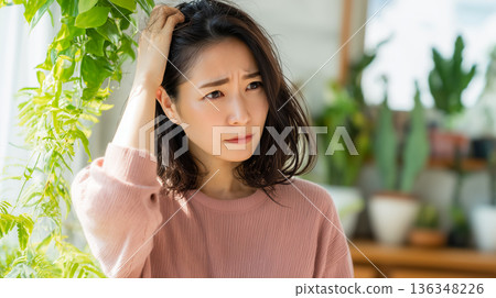 一位年輕女子因脫髮和頭髮受損而神情嚴肅。 136348226