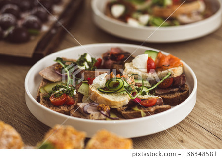 Assorted catering bruschetta with salmon, meat, and vegetables on a white plate. 136348581